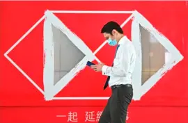  ?? ANTHONY WALLACE / AGENCE FRANCE-PRESSE ?? A MAN walks past an HSBC advert outside a branch of the bank in Hong Kong on 3 August 2020. HSBC says first half of 2020 profits has plunged 69 percent.