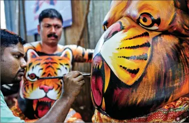  ??  ?? Artists paint performers with body paint as they prepare to take part in the ‘Pulikali’ or Tiger Dance in Thrissur on Sunday. AFP