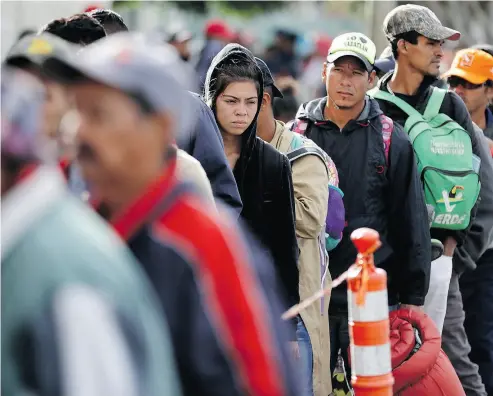  ?? GREGORY BULL/THE ASSOCIATED PRESS ?? Central American migrants wait in line for a meal at a shelter on Wednesday as the first sizable groups in the caravan fleeing violence in their home countries began arriving in the border city of Tijuana, Mexico.