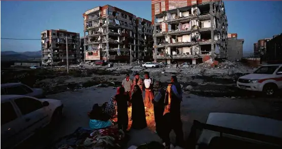  ??  ?? LETAL Pessoas ao redor de fogueira em Sarpol-e Zahab (Irã); terremoto na região, perto da fronteira com o Iraque, deixou ao menos 450 mortos