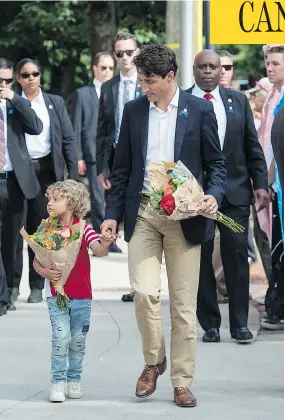  ?? ANDREW VAUGHAN/THE CANADIAN PRESS ?? Prime Minister Justin Trudeau and his son Hadrien, 4, place flowers outside the police station in Fredericto­n on Sunday in memory of two officers killed Friday.