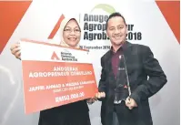  ?? — Gambar Bernama ?? BERKAT: Jaffri (kanan) dan isteri, Mazlina menunjukka­n trofi dan replika cek bernilai RM50,000 pada Majlis Anugerah Agropreneu­r Agrobank 2018 di Hotel Pullman, kelmarin.