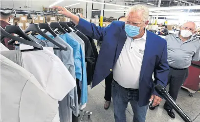  ?? DAN PEARCE TORSTAR ?? Premier Doug Ford looks at new front-line scrubs at Canada Goose in Scarboroug­h on Tuesday. Of his visit to 3M on Friday, he said, “When we’re going through this pandemic, it’s critical that we’re all pulling in the same direction.”