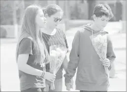  ??  ?? People pray on Tuesday before placing flowers at a sidewalk memorial to the teacher and student who were shot to death Monday at North Park Elementary School in San Bernardino.