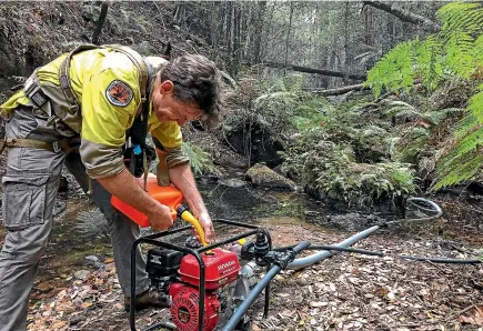  ?? NINE ?? A firefighte­r fuels a portable pump as he works in the Wollemi National Park.