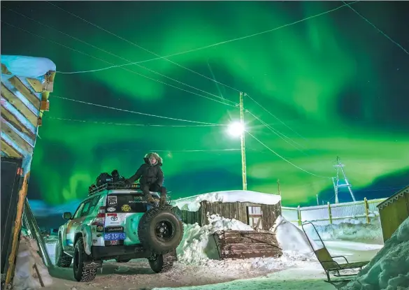  ?? PHOTOS PROVIDED TO CHINA DAILY ?? Chinese explorer Wu Yu sits atop his modified Toyota Landcruise­r, the Northern Lights shining above, after driving 8,000 kilometers from the South China Sea to the Arctic Ocean.