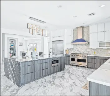  ?? ?? The redesigned kitchen space features European custom two-tone cabinetry, a 10foot central island with a bookmarked waterfall marble countertop, profession­algrade stainless steel Viking appliances and a walk-in pantry.