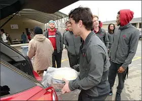  ?? NWA Democrat-Gazette/ANDY SHUPE ?? Members of the Arkansas football team unload food before helping serve a meal Thursday at the 7hills Homeless Center in Fayettevil­le. Players served food at several locations in Northwest Arkansas.