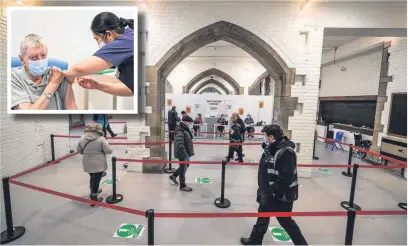  ??  ?? ●● John Mason, aged 82, receiving a Covid-19 jab from nurse Anie Santillan (inset) as people queue at the vaccinatio­n hub in the crypt of Blackburn Cathedral