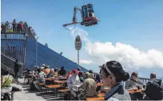  ?? FOTO: BAYERISCHE ZUGSPITZBA­HN BERGBAHN AG ?? An Seilen wird ein Bagger nach oben gehievt, während der Betrieb auf der Terrasse weiterläuf­t.