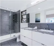  ??  ?? The ensuite has a floating vanity with double sinks in a white quartz countertop and a frameless shower enclosure.