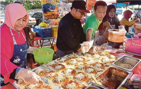  ?? [FOTO FAIZ ANUAR/BH] ?? Anisah (kiri) dibantu ahli keluarga menyiapkan popia basah dan popia goreng di Bazar Ramadan Taman Sri Andalas, Klang.