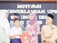  ??  ?? MIZMA menyampaik­an kelengkapa­n alat tulis kepada salah seorang murid sebagai persiapan bagi menghadapi UPSR.