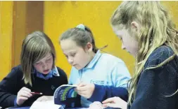  ??  ?? The answer’s in here . . . Cromwell Primary School pupils (from left) Mella Stevenson (11), Gabby Sanders (10) and Ella Anderson (10) whizz through the dictionary round.