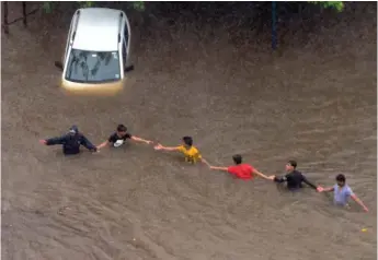  ?? —RAJESH JADHAV ?? People make a chain to wade through the flooded waters near King’s Circle as heavy rain disrupted normal life in Mumbai on Tuesday.