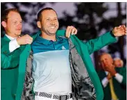  ?? ANDREW REDINGTON / GETTY IMAGES ?? Danny Willett, last year’s Masters champion, puts the green jacket on Sergio Garcia after the Spaniard earns his first major title in a playoff.