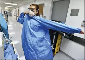  ?? BOB SELF — THE FLORIDA TIMES-UNION VIA AP ?? RN Zoe Zinis puts on fresh protective layers before entering the room of an infected patient in the COVID-19 ward at UF Health’s downtown in Jacksonvil­le, Fla., campus Friday, July 30. The second surge of COVID-19infectio­ns in Jacksonvil­le is stretching the capacity of area medical facilities to care for patients.