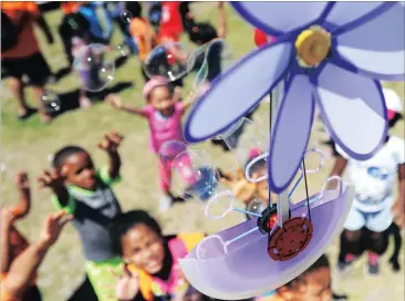  ?? Picture: BRENTON GEACH ?? BUBBLING OVER: Children at the Heideveld Sports Centre are entertaine­d by Ralf and Lucas Maserski from Germany, who bought a specially made aerial bubble machine for this year’s kite festival.