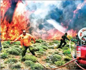  ?? VALERIE GACHE/AFP ?? Firefighte­rs and volunteers try to extinguish flames during a wildfire at the village of Kineta, near Athens, on Wednesday.