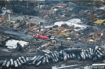  ?? Quebec. PAUL CHIASSON/THE CANADIAN PRESS 2013 ?? Workers comb through debris from a train derailment in Lac-Megantic,