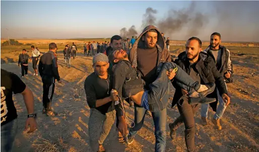  ?? AFP ?? Palestinia­n protesters carry an injured comrade during clashes with Israeli forces following a protest along the border with Israel, east of Gaza City on Sunday. —