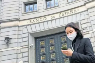  ?? REUTERS ?? Una mujer, protegida con una mascarilla, delante de la sede del Banco de España, en Madrid.