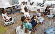  ??  ?? Dylan Durant (center foreground) joins classmates and teacher Meghan Davis in trying out new floor cushions in the redesigned classroom.