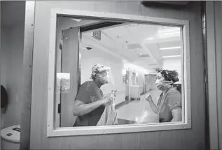  ??  ?? WASHINGTON, left, discusses how to handle a patient with fellow nurse Nicole Licup before slipping on her isolation gown. Washington, 31, is starting her career in the COVID-19 unit.