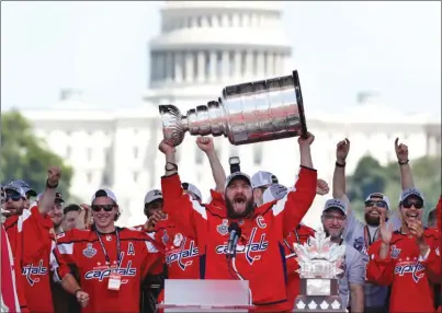  ?? The Associated Press ?? Washington Capitals captain Alex Ovechkin holds up the Stanley Cup trophy during the NHL team’s victory celebratio­n on Tuesday at the National Mall in Washington. Former Kelowna Rockets captain Madison Bowey, right, cheers on Ovechkin with the U.S....