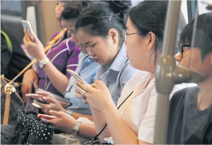  ?? APICHIT JINAKUL ?? Skytrain passengers on their mobile phones. Mobile virtual network operators have presented a list of amendments for the regulator to consider.