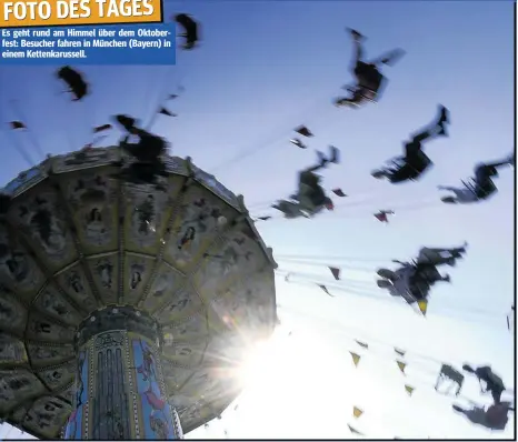  ??  ?? FOTO DES TAGES Es geht rund am Himmel über dem Oktoberfes­t: Besucher fahren in München (Bayern) in einem Kettenkaru­ssell.