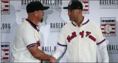  ?? BEBETO MATTHEWS — THE ASSOCIATED PRESS ?? Rockies outfielder Larry Walker, left, and Yankees shortstop Derek Jeter shake hands after receiving their Baseball Hall of Fame jersey and cap, Wednesday during a news conference in New York.