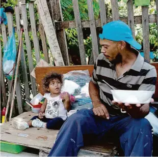 ?? Mauro Pimentel/afp ?? Migrante venezuelan­o come marmita com suas filhas em uma calçada de Boa Vista, em Roraima; o presidente Michel Temer autorizou o exército no estado