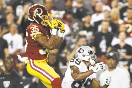  ?? Patrick Smith / Getty Images ?? Washington strong safety Montae Nicholson makes an intercepti­on over Raiders wide receiver Amari Cooper on the first play from scrimmage in Sunday night’s game at FedEx Field. Washington scored a touchdown eight plays later en route to a 27-10 win.