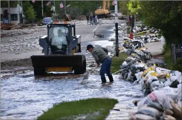  ?? MATTHEW BROWN — THE ASSOCIATED PRESS ?? Residents of Red Lodge, Montana, are seen clearing mud, water and debris from the small city's main street on Tuesday, after flood waters coursed through a residentia­l area with hundreds of homes.