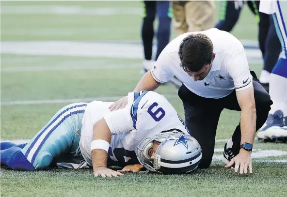  ?? — THE ASSOCIATED PRESS FILES ?? Dallas Cowboys quarterbac­k Tony Romo is tended to by a trainer after being hurt during an NFL pre-season game against the Seahawks Thursday in Seattle. Romo could be out six to 10 weeks after suffering a broken bone in his back.