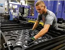  ?? THOMAS GNAU / STAFF ?? Michael Lensman arranges gears after cutting them on a Crown Equipment assembly line in New Bremen.