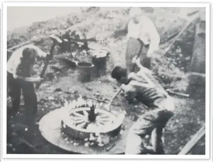  ?? ?? Fred Stacey watching his son Frederick and John Kerley in the early 1940s as they hammer a heated iron tyre on a cartwheel prior to dousing it with water to cool and shrink it on the felloes