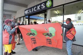  ?? Picture: ANDIS BONANI ?? ANTI RACISM: Members of the EFF Chris Hani region sing revolution­ary songs outside the Cathcart Road Clicks in Komani before storming into the store and destroying merchandis­e