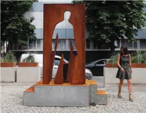  ??  ?? A woman walks past the monument in Moscow honouring delivery couriers who continued to work throughout the coronaviru­s outbreak, helping people cope with the stringent self-isolation regime.