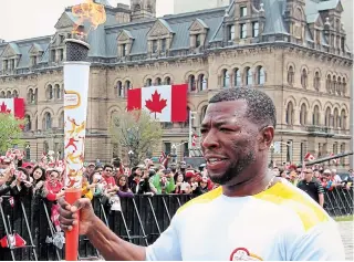  ?? CANADIAN PRESS FILE PHOTO ?? Former Canadian sprinter Glenroy Gilbert carries the Pan Am torch during Canada Day celebratio­ns on Parliament Hill in Ottawa on July 1, 2015.