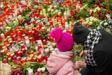  ?? ?? Mourners gather Friday outside the headquarte­rs of Charles University. Czech police will bolster patrols at places with large gatherings of people during the holiday season.