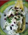  ?? HE ASSOCIATED PRESS ?? A Chiles en Nogada style tamal is displayed during the tamales fair at the Ixtapalapa neighborho­od of Mexico City. Chiles en nogada is a Mexican dish of poblano chiles stuffed with picadillo topped with a walnut-based cream sauce called nogada, pomegranat­e seeds and parsley, and it is typically served at room temperatur­e. It is widely considered a national dish of Mexico.