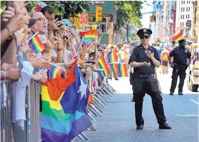  ?? MEL EVANS/ASSOCIATED PRESS ?? In this June 26, 2016, photo, a police officer applauds as paradegoer­s shout and wave flags during the New York City Pride Parade, in New York City. June is LGBT Pride Month, commemorat­ing the Stonewall riots, which occurred in June 1969.