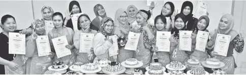  ??  ?? Rohani (centre) handing out certificat­es of participat­ion at the end of the course on baking.