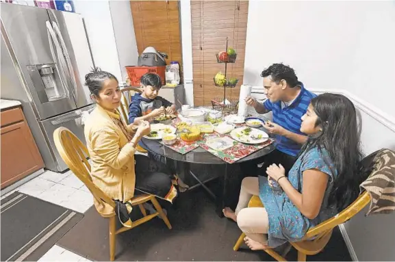  ?? KENNETH K. LAM/BALTIMORE SUN ?? Mohan Shahi, his wife, Sabitri Chand, and their two children, Swumya, 11, and Swornim, 8, have dinner in their new home in Elkridge.
