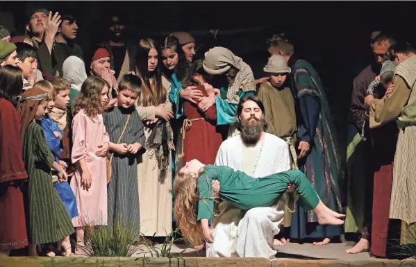  ??  ?? Jesus, kneeling, portrayed by David Ericson, heals a child during a live Easter production at Fellowship Baptist Church in Columbus on Wednesday. The church made the decision months ago to move forward with the drama, despite uncertaint­y about what pandemic life would be like this Easter.