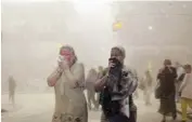  ?? AP PHOTO/SUZANNE PLUNKETT ?? People covered in dust from the collapsed World Trade Center buildings walk through the area in New York on Sept. 11, 2001.