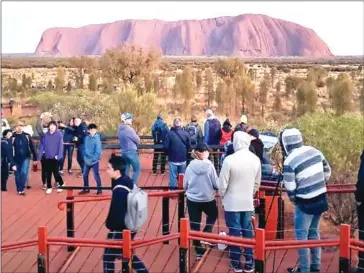  ?? HANDOUT/@KOKI_MEL_AUS/AFP ?? Tourists looking at Uluru in Australia’s Northern Territory.