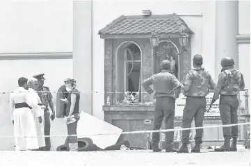  ?? — AFP photo ?? A foreign investigat­or (fourth left) talks with priests as soldiers stand guard at St. Anthony’s Shrine in Colombo.